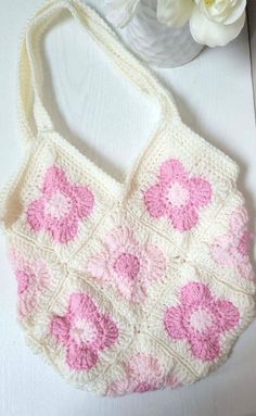 a crocheted bag sitting on top of a table next to a flower vase