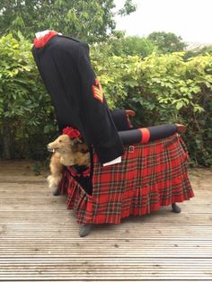 a dog sitting on top of a table with a tartan jacket over it's head