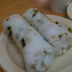 two burritos sitting on a plate next to a cup