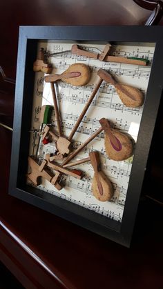 a group of wooden spoons sitting on top of musical paper in a shadow box