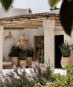 an outdoor patio with potted plants and wicker umbrellas hanging from the roof