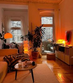 a living room filled with lots of furniture next to a window covered in plants and candles