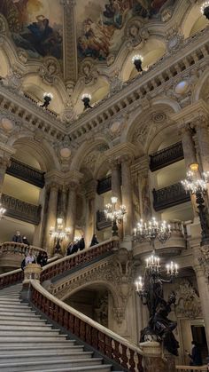 an ornate staircase with chandeliers and paintings on the ceiling