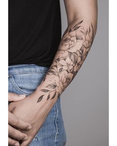 a man's arm with flowers on it and his hand holding the other arm