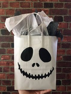 a hand holding a white bag with a skull on it's face and black eyes