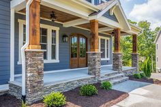 a blue house with stone pillars and columns on the front porch is pictured in this image