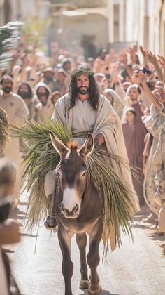 a man riding on the back of a donkey down a street with people in the background