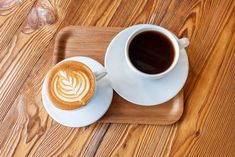 two cups of coffee sitting on top of a wooden tray