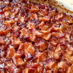 a casserole dish filled with bacon on top of a wooden table