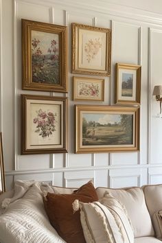 a living room filled with lots of framed pictures on the wall above a white couch