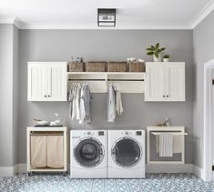 a washer and dryer in a laundry room with cabinets on the wall above them