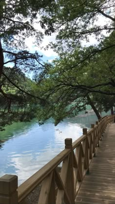 a wooden bridge over a body of water with trees on both sides and people walking across the bridge