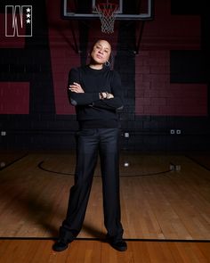 a woman standing in front of a basketball hoop with her arms crossed and looking at the camera