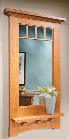 a wooden shelf with a mirror and vase on it