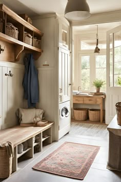 a clean and organized laundry room with lots of natural wood storage, hanging baskets, and rugs