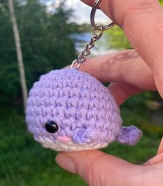 a hand holding a tiny purple crocheted animal keychain