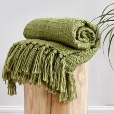 a green blanket sitting on top of a wooden post next to a plant in a pot