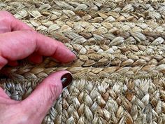 a hand is holding the edge of a piece of woven material that has been placed on top of it