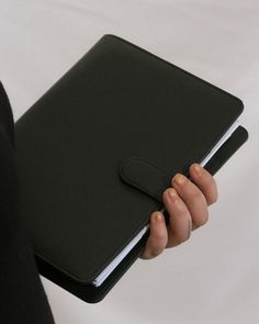 a person holding a black notebook in their hand