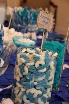 blue and white candies are in glass containers on a table with other candy items