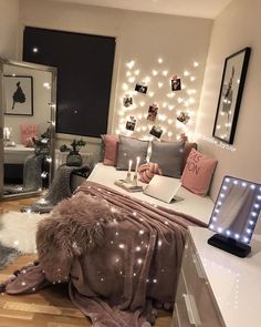 a bedroom decorated in pink and grey with lights on the wall, bedding and rugs