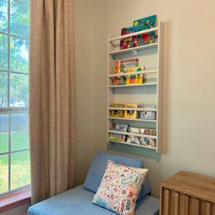 a blue couch sitting in front of a window next to a book shelf