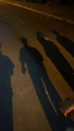 the shadows of people are cast on the street as they ride their skateboards at night