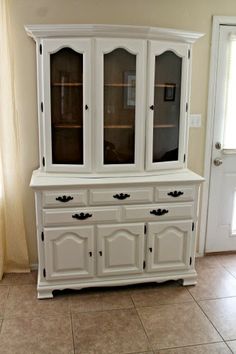 a white china cabinet sitting on top of a tiled floor