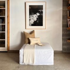 a room with a couch, bookshelf and pictures on the wall above it