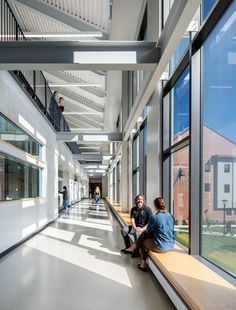 two people sitting on a bench in an empty building with large windows and skylights