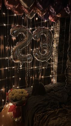 balloons and streamers are hanging from the ceiling above a bed in a dark room