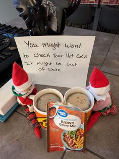 two elf hats sitting on top of cups next to a sign that says you might want to cheer your hot cocoa