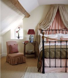 a bed sitting in a bedroom next to a window with curtains on the top of it