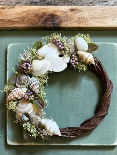 a wreath with seashells and seaweed is hung on a green door frame