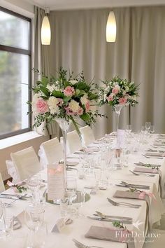 the table is set with white linens and pink flowers