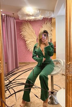 a woman taking a selfie while sitting on a stool in front of a mirror