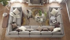 an overhead view of a living room with grey couches and white pillows on the floor