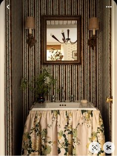 a bathroom sink sitting under a mirror next to a wallpapered wall with flowers on it