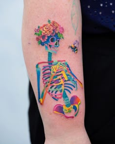 a person with a tattoo on their arm that has a skeleton and flowers on it