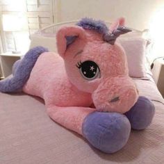 a pink stuffed unicorn laying on top of a bed