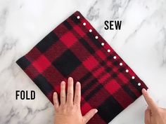 someone is pointing at a red and black plaid cloth