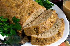 sliced meatloaf on a white plate with parsley next to it and a glass of orange juice