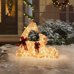 an outdoor christmas scene with a lighted deer sitting on the ground and lights in the background