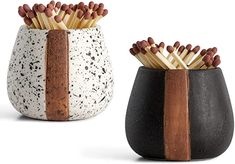 two black and white ceramic vases with matches in them, one is filled with matchsticks