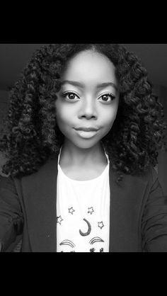 a black and white photo of a young woman with curly hair wearing a blazer