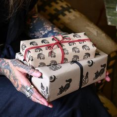 a tattooed person holding two wrapped presents