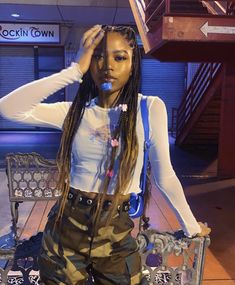 a woman with dreadlocks is sitting on a bench and posing for the camera