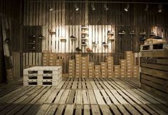 a room filled with lots of wooden pallets next to a wall covered in shelves