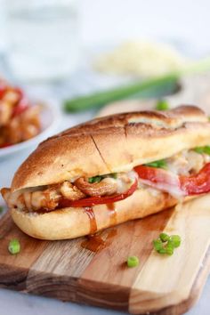 a sandwich with meat and tomatoes on a cutting board