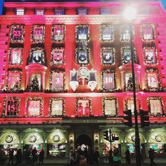 the building is decorated with christmas lights and clock faces on it's side at night